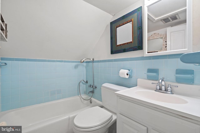 bathroom with vanity, toilet, and tile walls