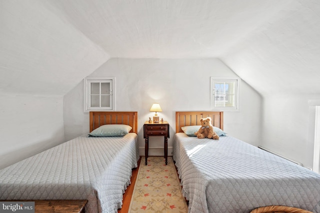 carpeted bedroom featuring baseboard heating and lofted ceiling