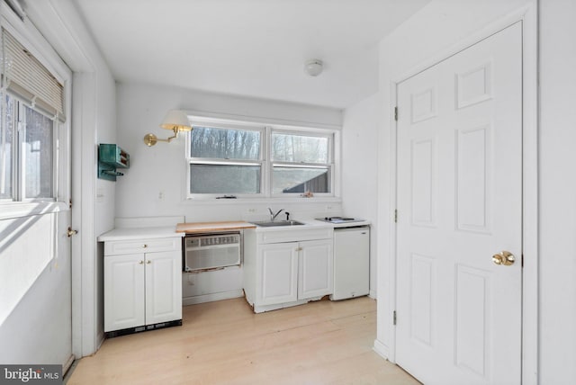 kitchen with sink, white cabinetry, an AC wall unit, light wood-type flooring, and white dishwasher