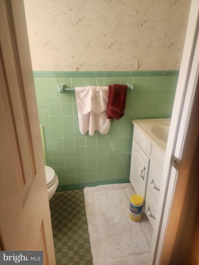 bathroom with tile patterned flooring, vanity, tile walls, and toilet