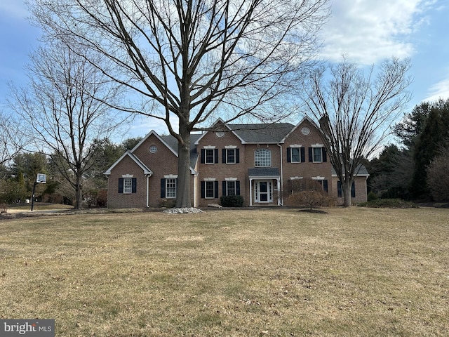 view of front facade featuring a front yard, brick siding, and a chimney