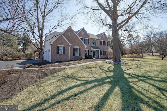 view of front of home featuring a garage, brick siding, and a front lawn