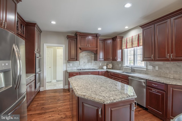 kitchen featuring dark wood finished floors, backsplash, stainless steel appliances, and a sink