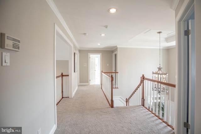 hallway with an upstairs landing, an inviting chandelier, carpet flooring, and crown molding