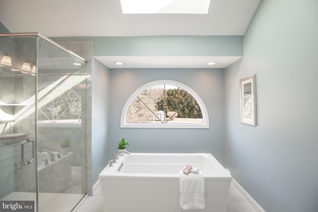 bathroom featuring recessed lighting, a soaking tub, a shower stall, and a skylight