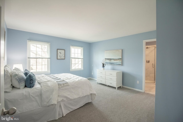 carpeted bedroom with ensuite bathroom and baseboards