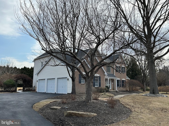 view of front of home with aphalt driveway, brick siding, and a garage