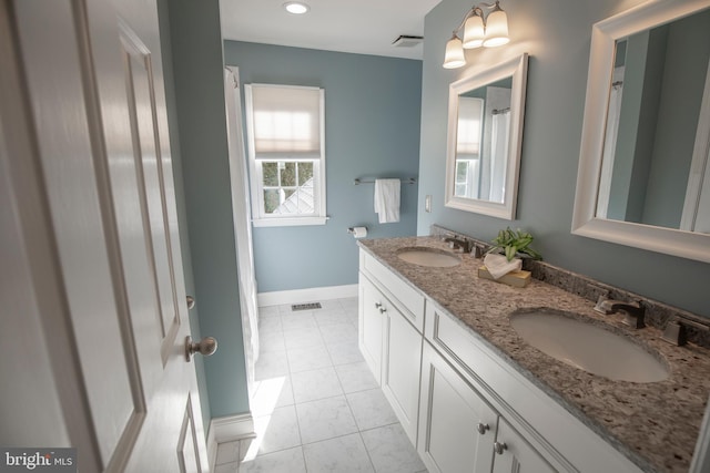 bathroom with baseboards, visible vents, and a sink