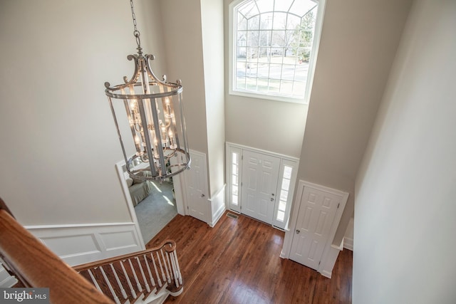 foyer entrance with a decorative wall, wood finished floors, wainscoting, and a chandelier