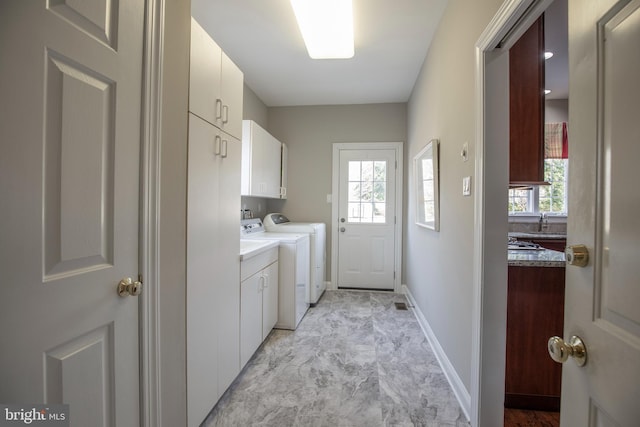 laundry room featuring baseboards, cabinet space, separate washer and dryer, and a healthy amount of sunlight