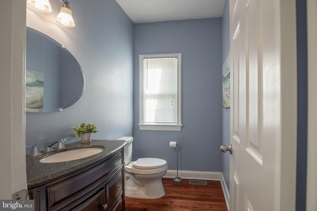 bathroom featuring visible vents, toilet, wood finished floors, baseboards, and vanity