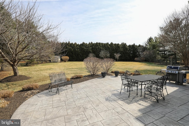 view of patio / terrace featuring grilling area, a storage unit, outdoor dining area, and an outdoor structure