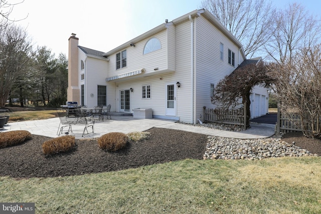 back of house featuring a lawn, a chimney, and a patio area