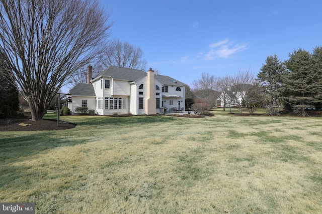 rear view of property with a chimney and a yard