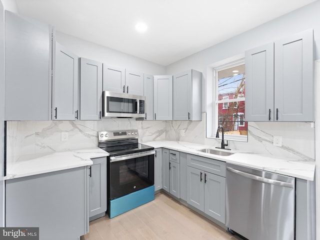 kitchen featuring gray cabinets, appliances with stainless steel finishes, sink, and decorative backsplash