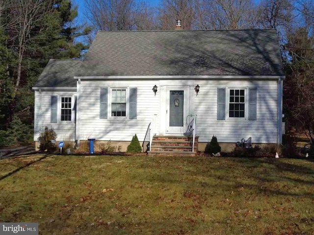 new england style home featuring entry steps, roof with shingles, and a front yard