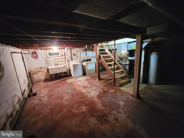 unfinished below grade area featuring washing machine and dryer, a sink, and stairway