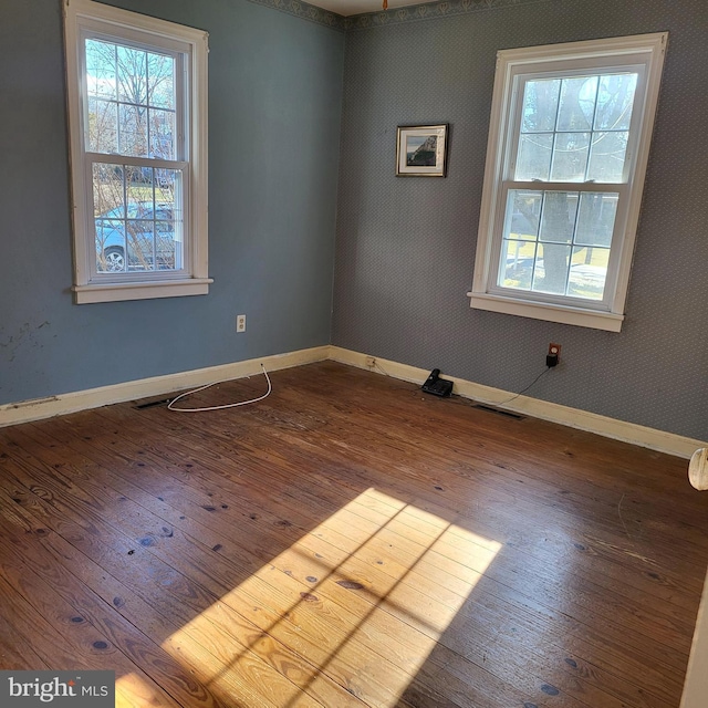 empty room featuring baseboards and dark wood-type flooring