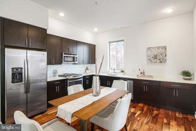 kitchen featuring sink, dark wood-type flooring, backsplash, dark brown cabinets, and stainless steel appliances