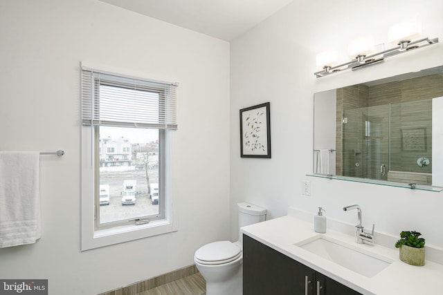 bathroom with vanity, toilet, and a shower with door