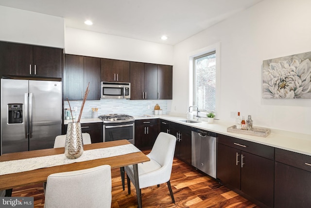 kitchen with sink, dark brown cabinets, dark hardwood / wood-style flooring, stainless steel appliances, and backsplash