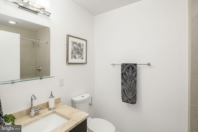 bathroom with vanity, a tile shower, and toilet