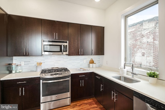 kitchen with dark wood-type flooring, sink, tasteful backsplash, dark brown cabinets, and appliances with stainless steel finishes