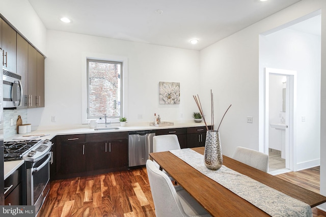 kitchen featuring sink, appliances with stainless steel finishes, dark brown cabinets, tasteful backsplash, and dark hardwood / wood-style flooring