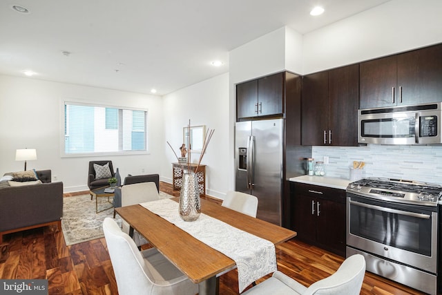 kitchen with dark brown cabinetry, backsplash, dark wood-type flooring, and stainless steel appliances