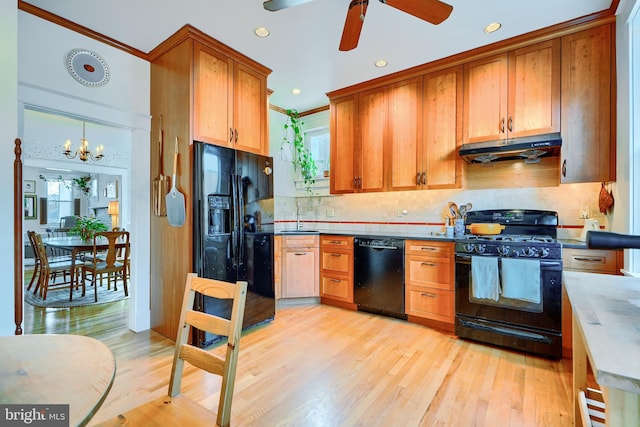 kitchen with a sink, black appliances, under cabinet range hood, light wood-type flooring, and backsplash