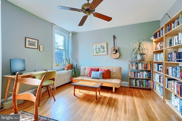 living area with radiator heating unit, a ceiling fan, and wood finished floors