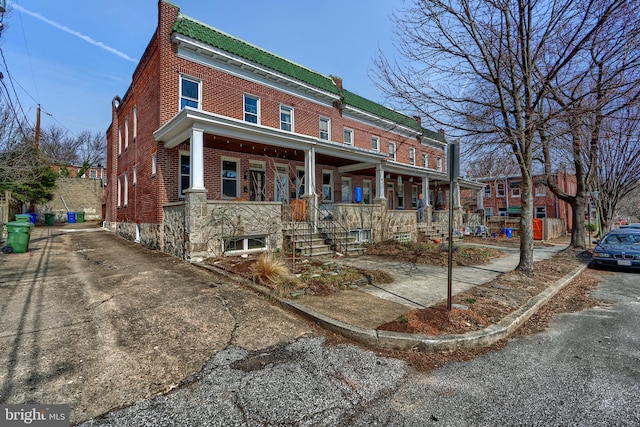 townhome / multi-family property featuring brick siding, a porch, and a chimney