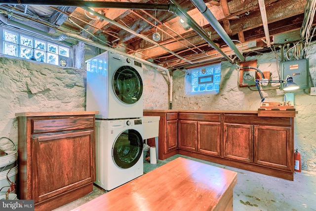 clothes washing area with cabinet space and stacked washer and clothes dryer