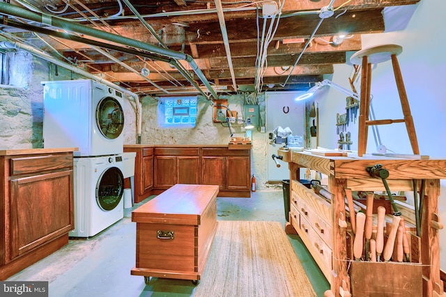 below grade area featuring electric panel and stacked washer / dryer