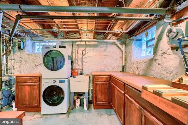 clothes washing area with cabinet space and stacked washer / dryer