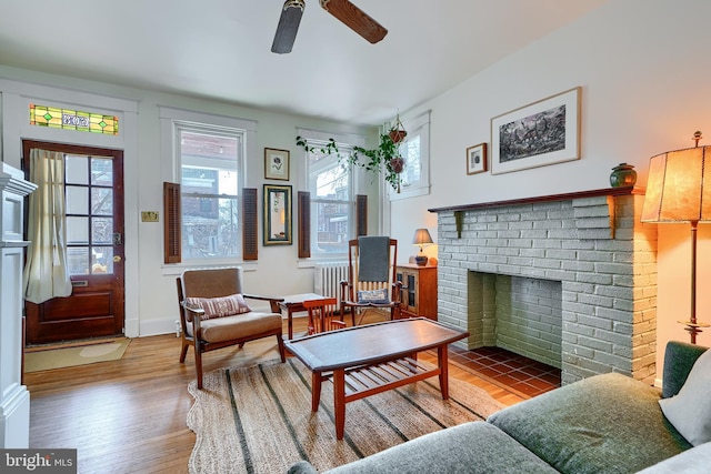 living room featuring a healthy amount of sunlight, a fireplace, ceiling fan, and wood finished floors