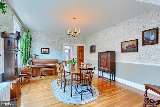 dining area with wallpapered walls, a notable chandelier, radiator heating unit, and light wood-style floors