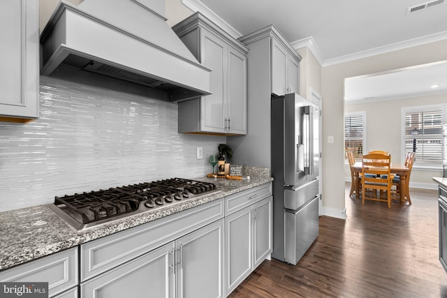 kitchen featuring dark wood-type flooring, custom exhaust hood, crown molding, tasteful backsplash, and stainless steel appliances