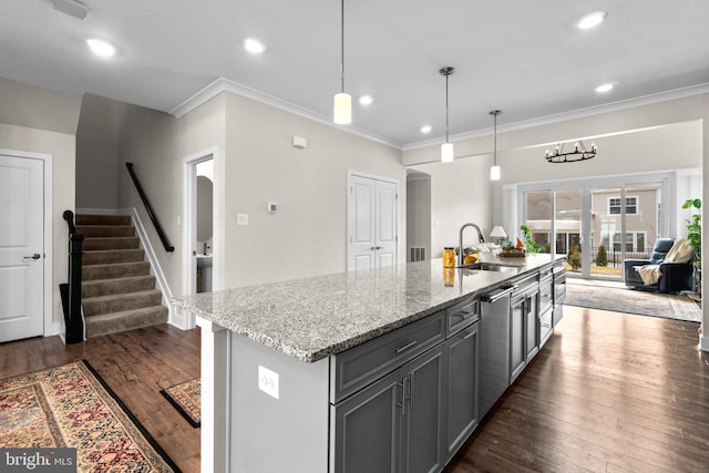 kitchen featuring an island with sink, stainless steel dishwasher, pendant lighting, and gray cabinetry