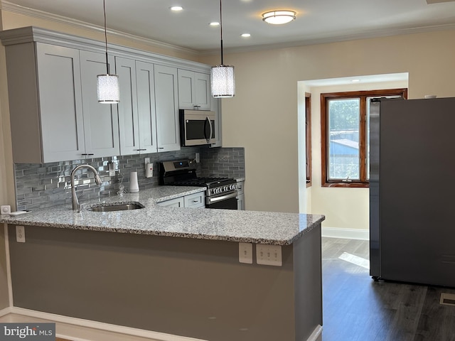 kitchen with pendant lighting, appliances with stainless steel finishes, light stone countertops, and sink