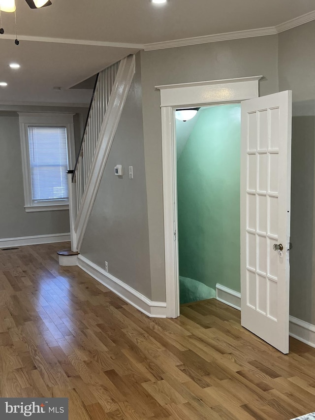 spare room with crown molding, wood-type flooring, and ceiling fan