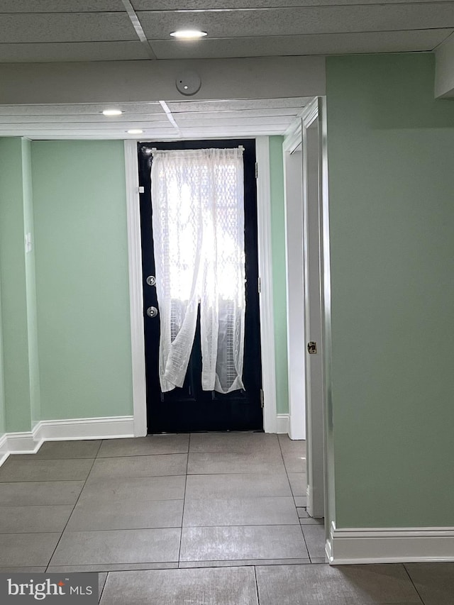 interior space with a paneled ceiling and tile patterned floors