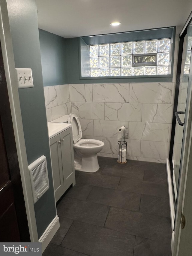 bathroom featuring vanity, an enclosed shower, tile walls, and toilet