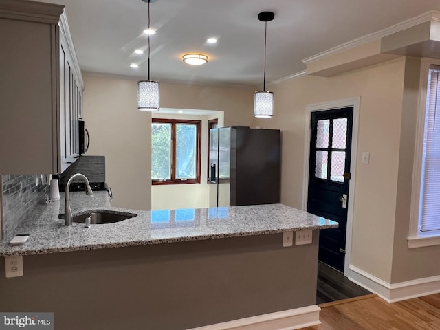 kitchen with light stone counters, appliances with stainless steel finishes, decorative light fixtures, and sink