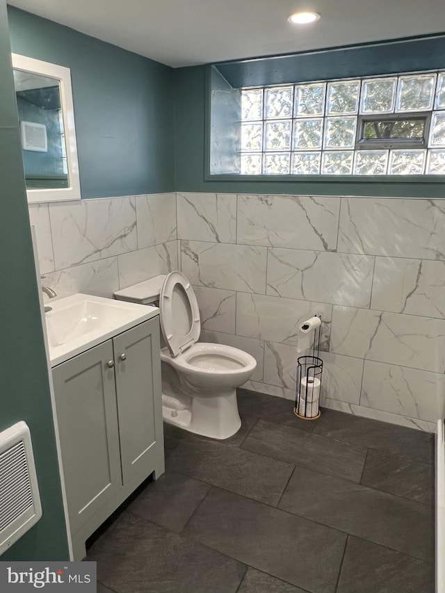 bathroom featuring vanity, tile walls, and toilet