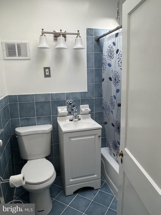 full bathroom featuring shower / tub combo with curtain, tile walls, vanity, tile patterned floors, and toilet