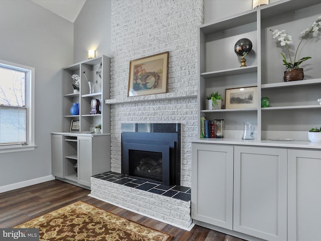 living room featuring a brick fireplace and dark hardwood / wood-style flooring