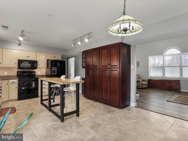 kitchen with pendant lighting, cream cabinets, and black appliances