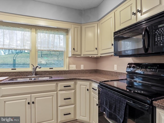 kitchen with cream cabinets, sink, dark stone countertops, and black appliances