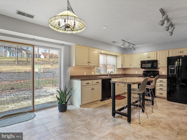 kitchen featuring sink, decorative light fixtures, black appliances, and cream cabinetry